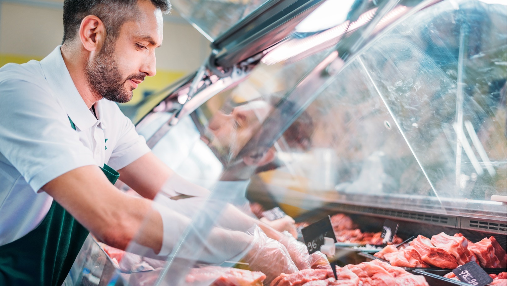 shop-assistant-in-apron-assorting-fresh-raw-meat-i-2021-08-29-12-16-52-utc