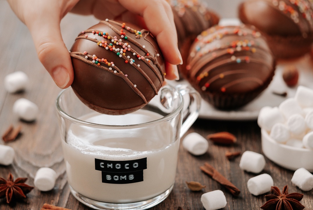 chocolate-cocoa-bomb-or-ball-in-hand-near-milk-cup-2021-10-13-23-53-37-utc