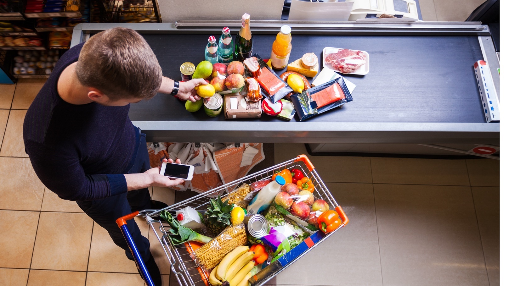 young-man-putting-goods-on-counter-in-supermarket-2021-08-26-22-40-13-utc