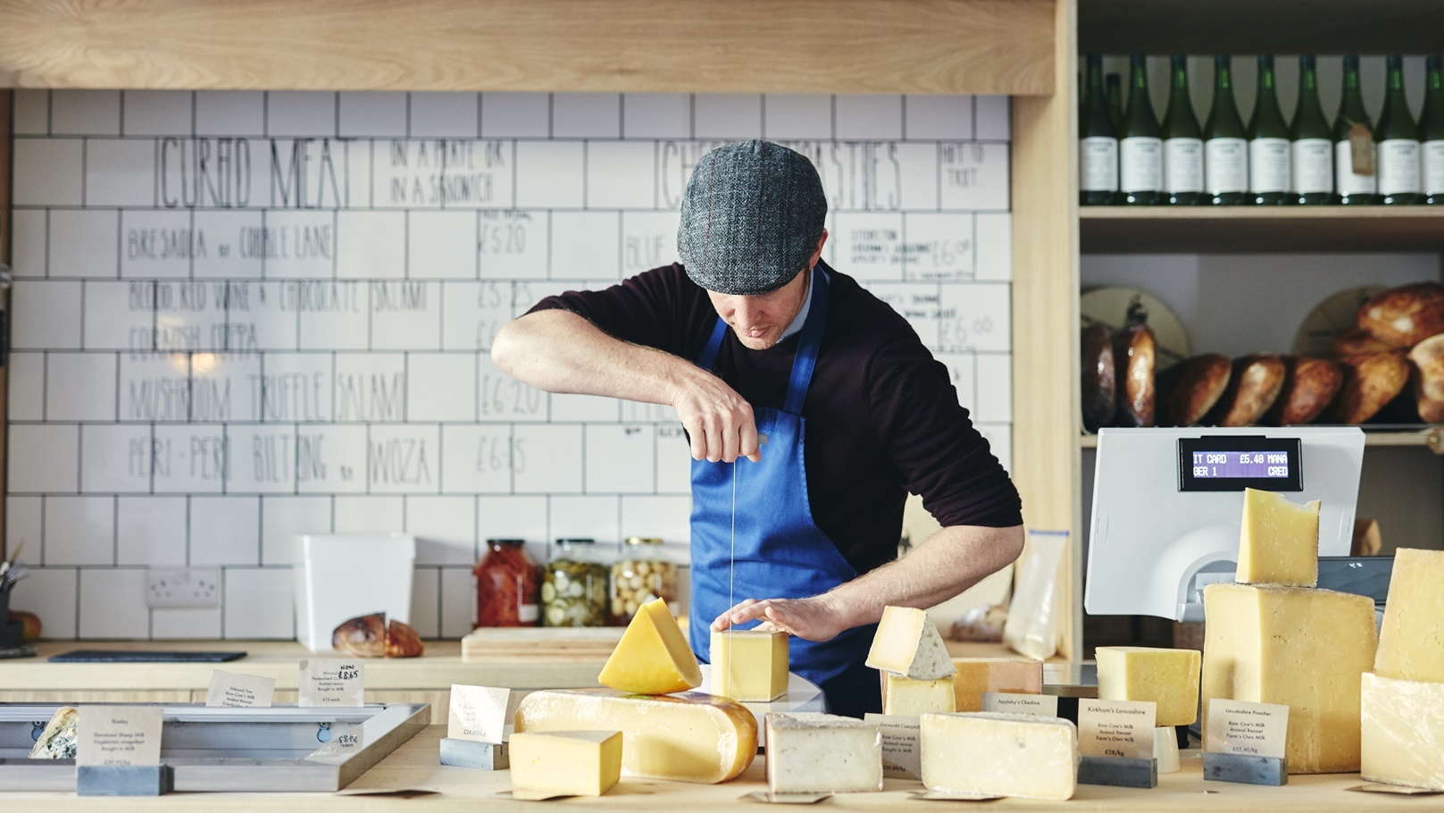 cheesemonger-cutting-cheese-with-cheese-wire-surro-2022-03-04-02-06-07-utc