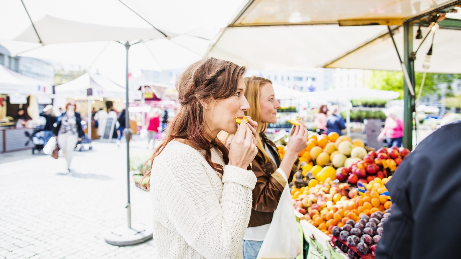 women-eating-fruit-while-shopping-at-market-2021-08-29-00-57-25-utc