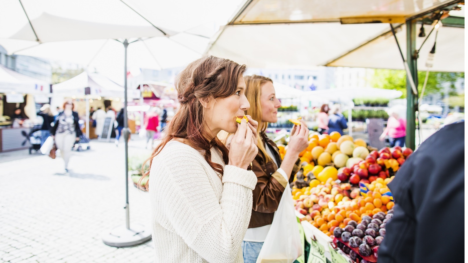 women-eating-fruit-while-shopping-at-market-2021-08-29-00-57-25-utc