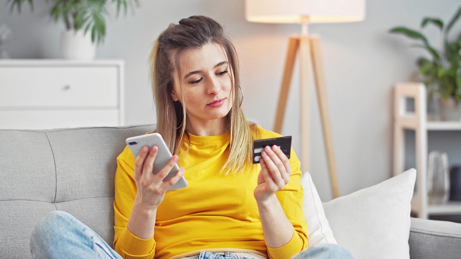 young-woman-using-smartphone-and-credit-card-shopp-2021-09-08-11-17-55-utc