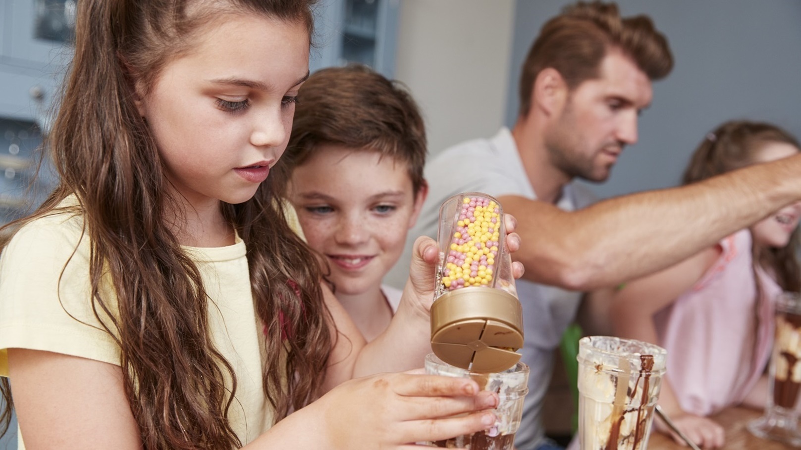 father-making-ice-cream-sundaes-with-children-at-h-2021-08-26-16-13-52-utc