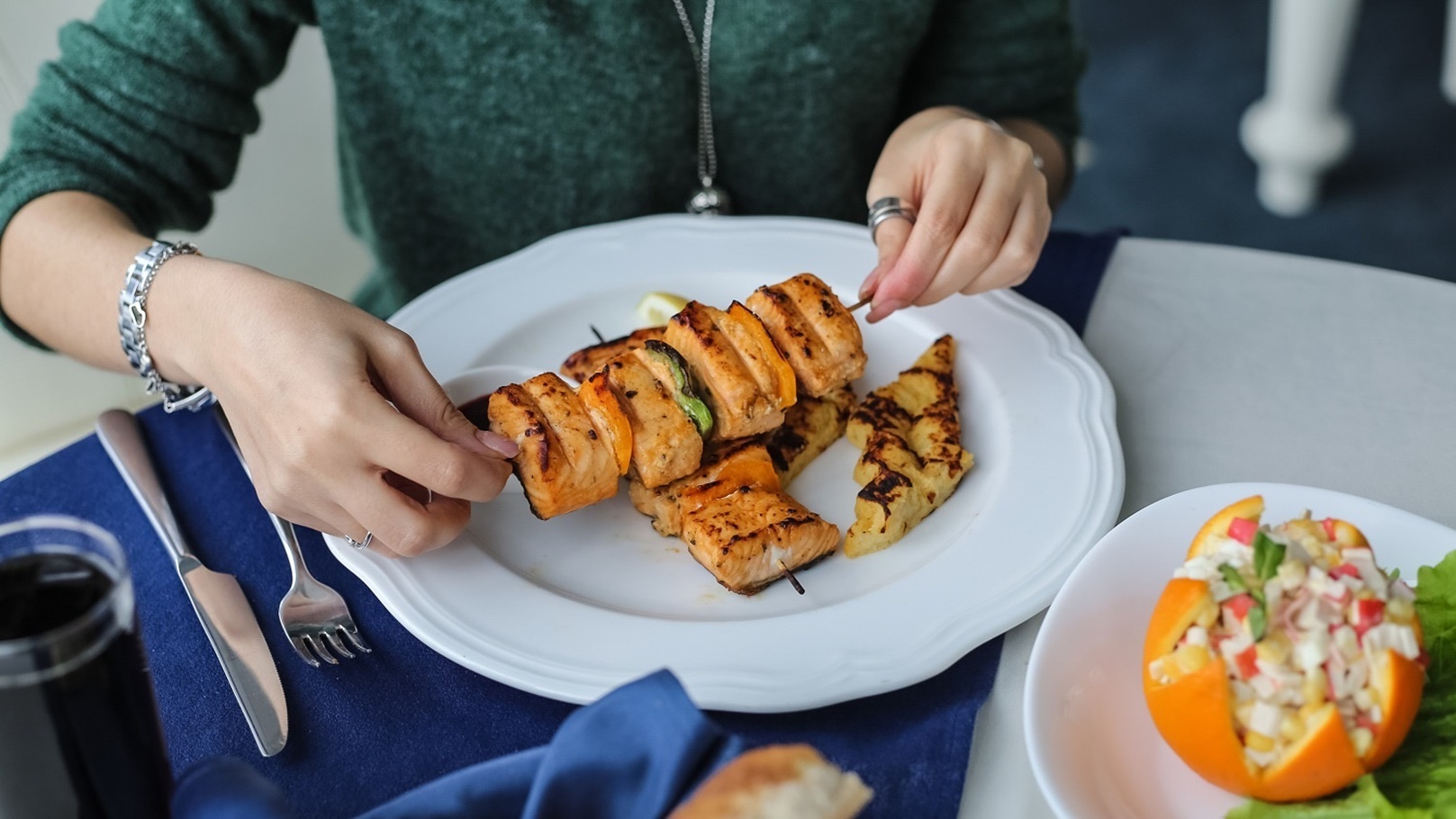 side-view-woman-eating-grilled-fish-on-skewers-wit-2021-08-31-16-12-55-utc