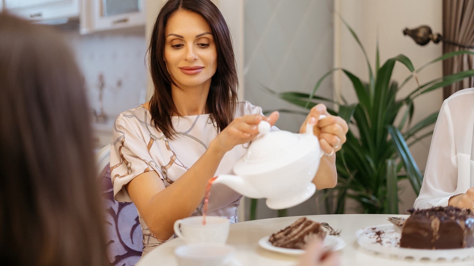 woman-pouring-tea-from-a-white-teapot-at-home-2022-01-19-19-57-47-utc