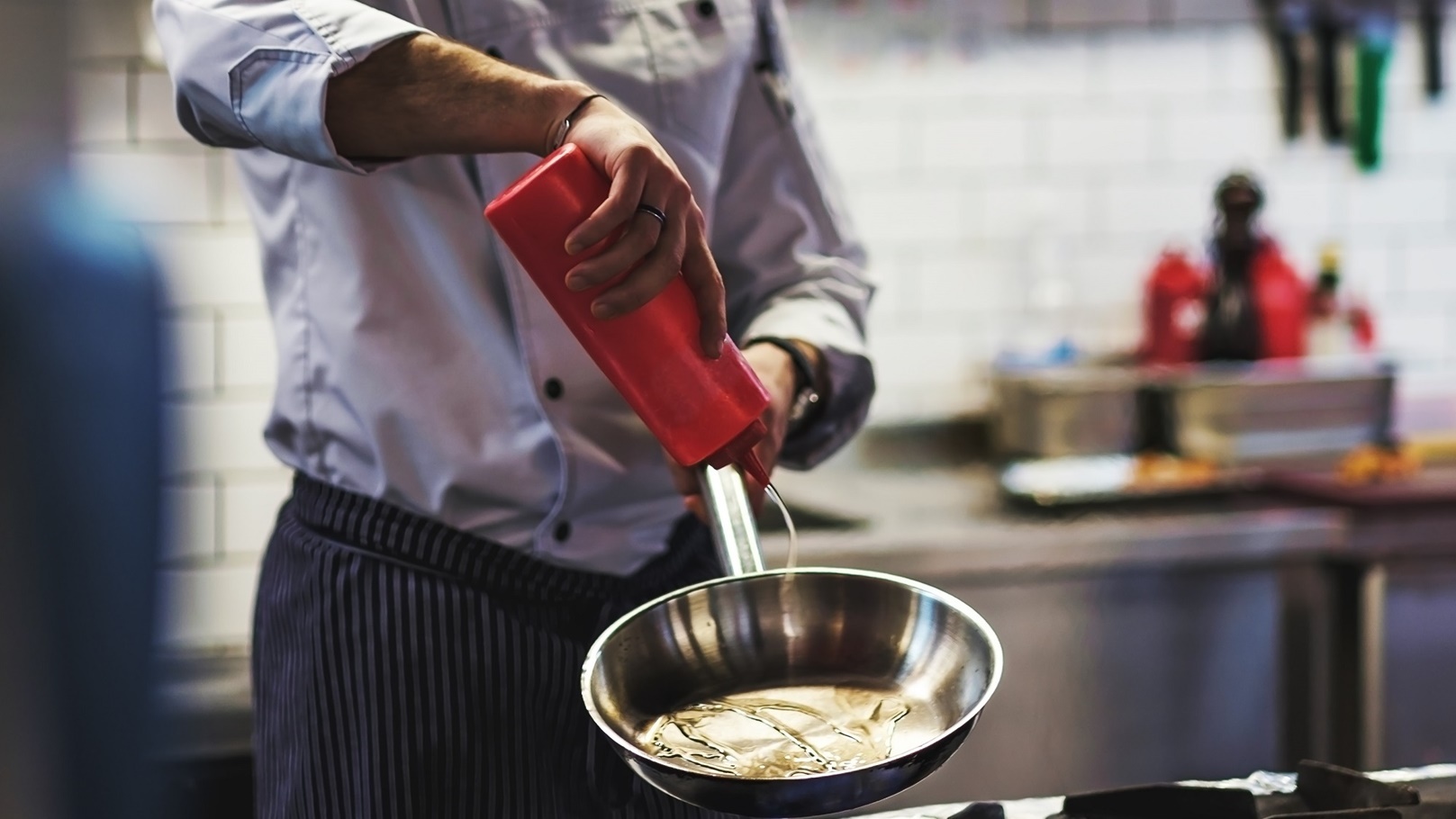 caucasian-chef-hand-pours-vegetable-oil-on-a-fryin-2021-08-26-15-50-36-utc