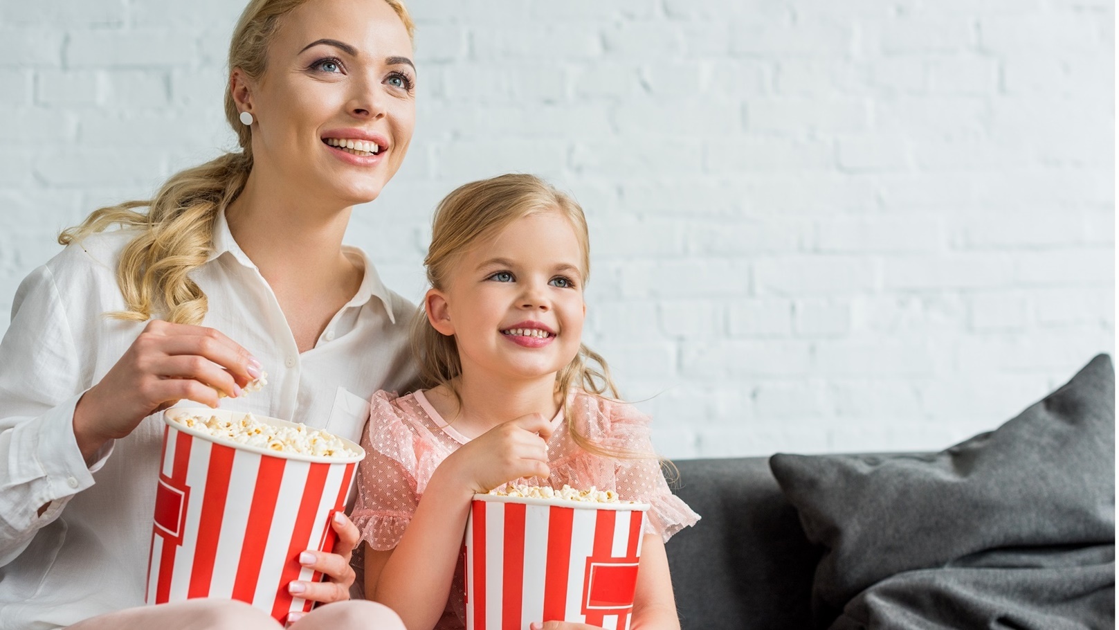 happy-mother-and-daughter-eating-popcorn-and-looki-2022-01-19-00-05-10-utc