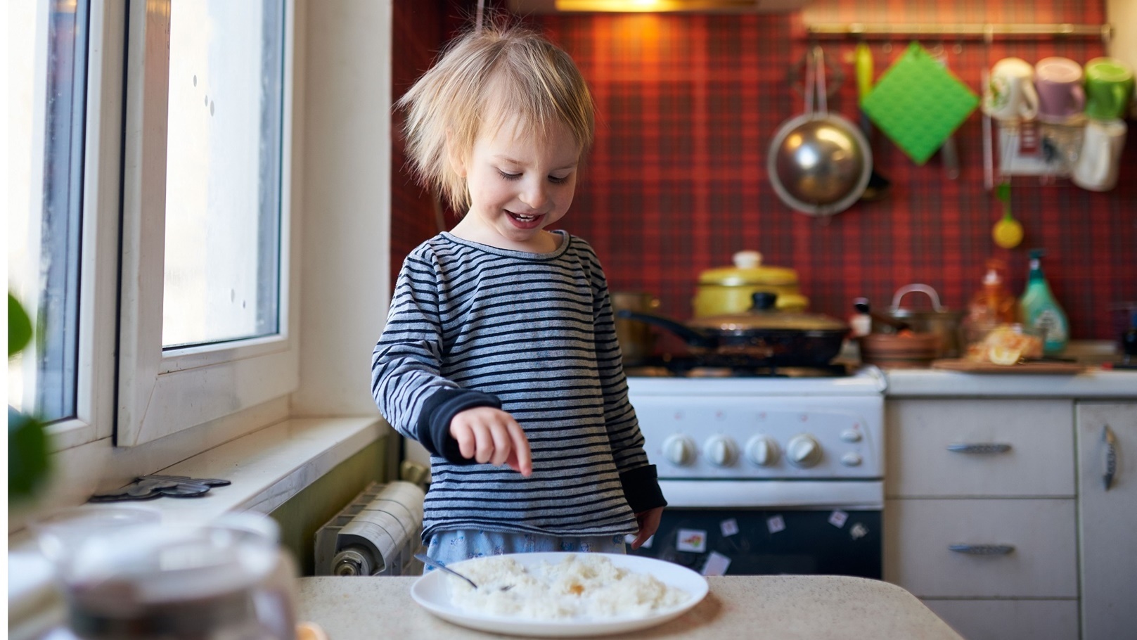 funny-blond-baby-eating-rice-on-kitchen-2022-01-24-19-53-34-utc