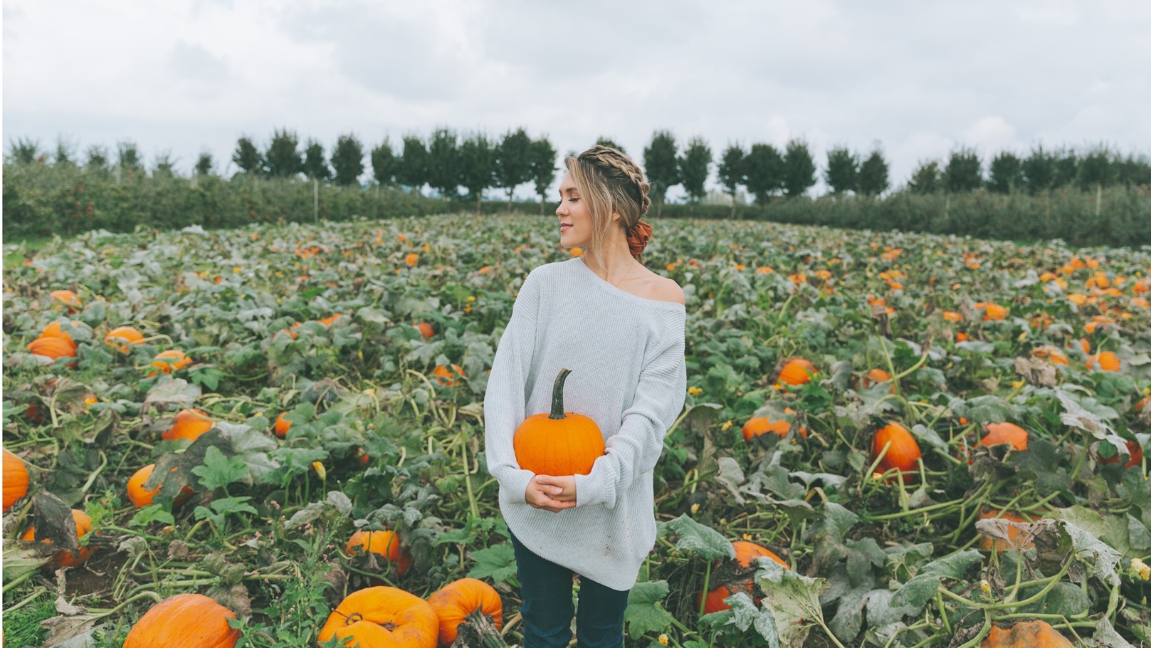 a-woman-holding-a-pumpkin-in-a-pumpkin-patch-2021-08-26-20-17-14-utc