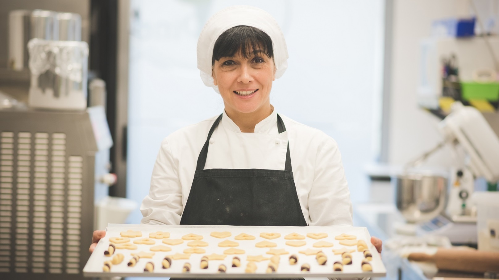 baker-carrying-tray-of-pastries-in-kitchen-2022-03-04-01-47-02-utc