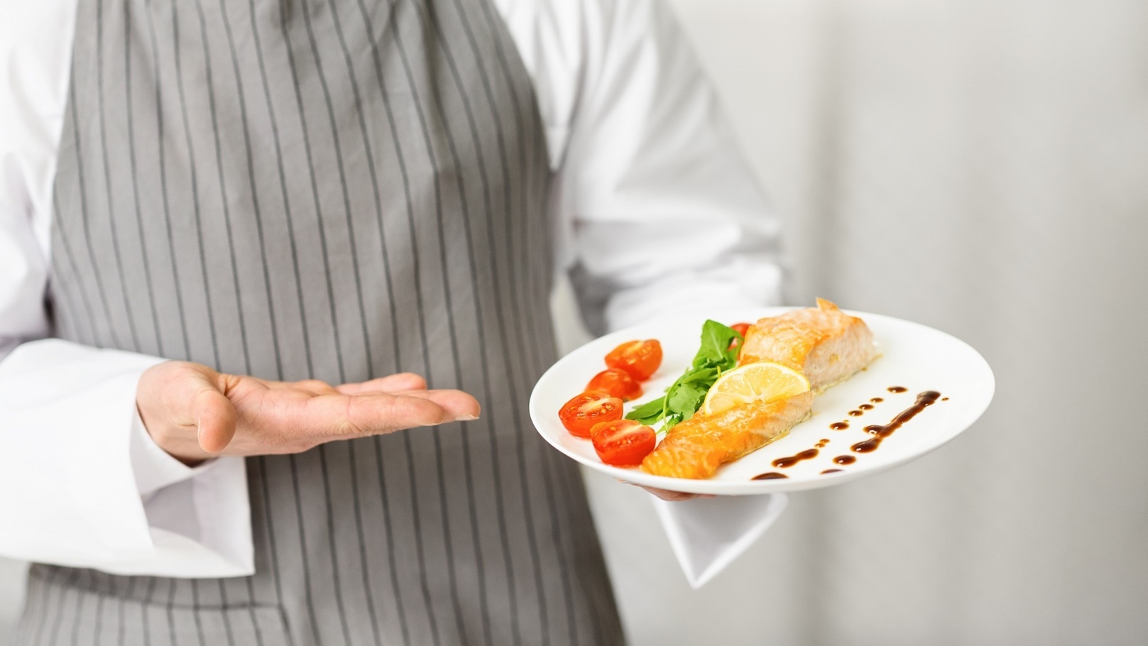 unrecognizable-chef-holding-plate-with-fish-steak-2021-08-27-09-43-40-utc