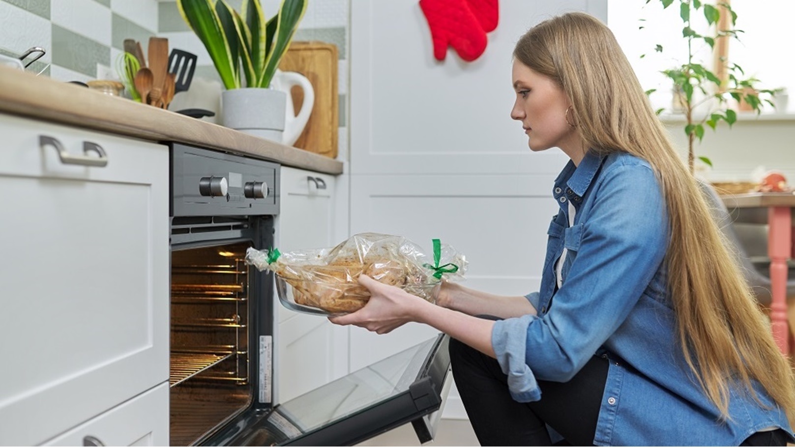 young-woman-putting-marinated-chicken-in-baking-ba-2022-03-09-22-03-12-utc