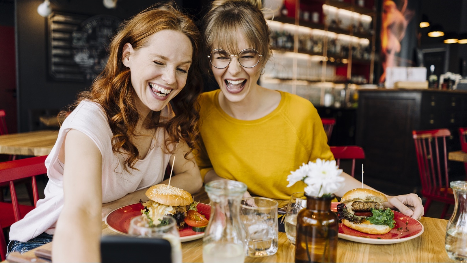 two-happy-female-friends-having-burger-and-taking-2022-03-08-01-25-05-utc