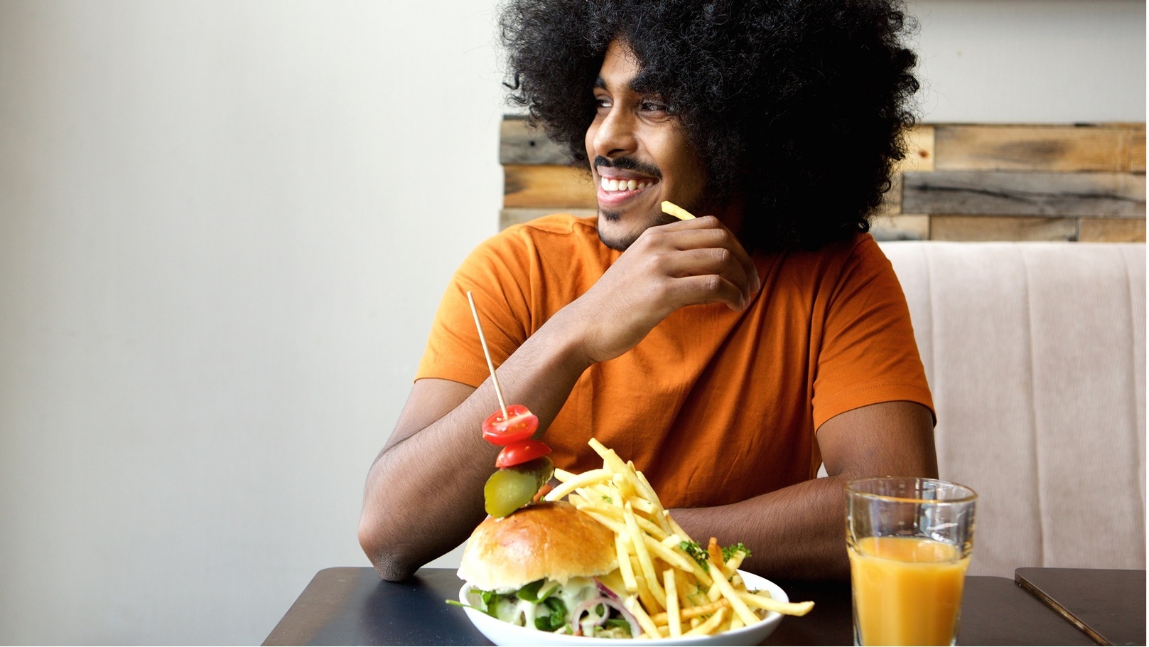 smiling-man-with-hamburger-and-fries-at-restaurant-2021-08-26-23-05-16-utc