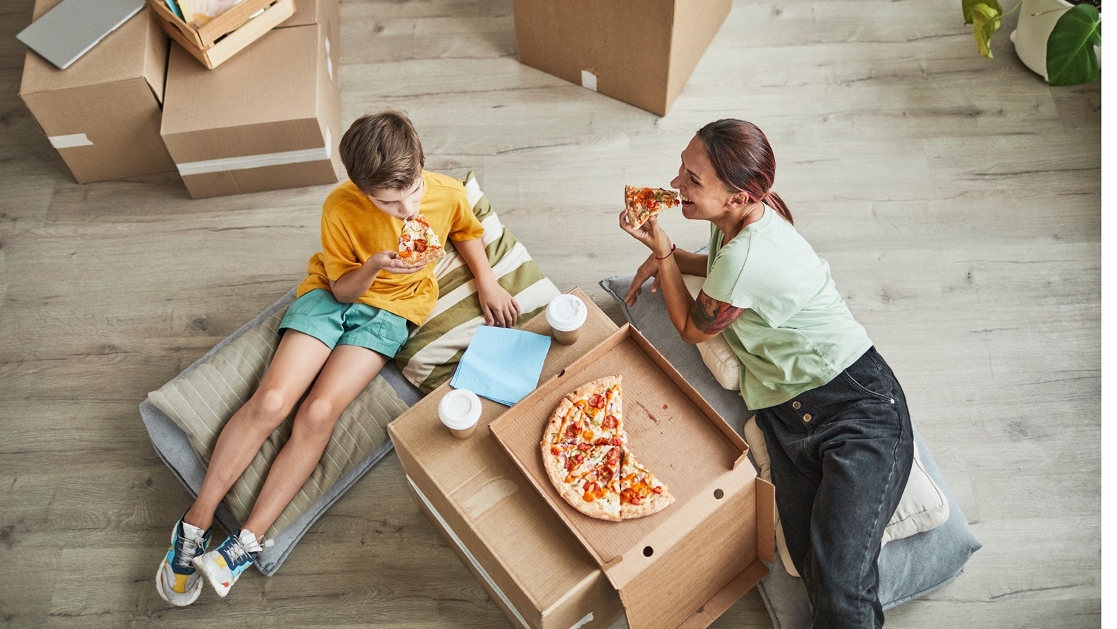mother-and-son-eating-pizza-in-new-home-high-angle-2022-01-18-23-58-43-utc