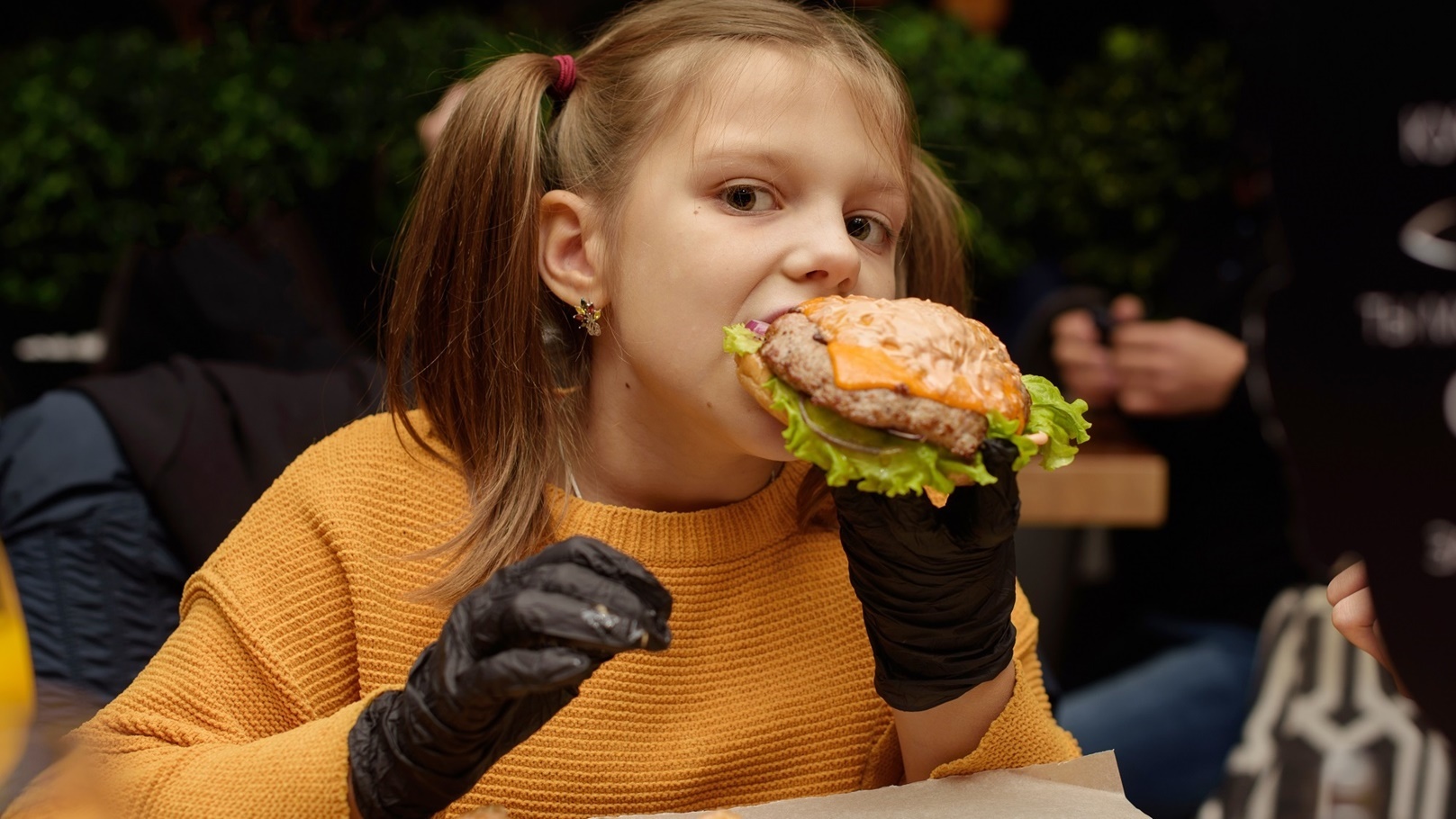 a-girl-eats-a-burger-with-black-gloves-2021-08-29-14-53-27-utc