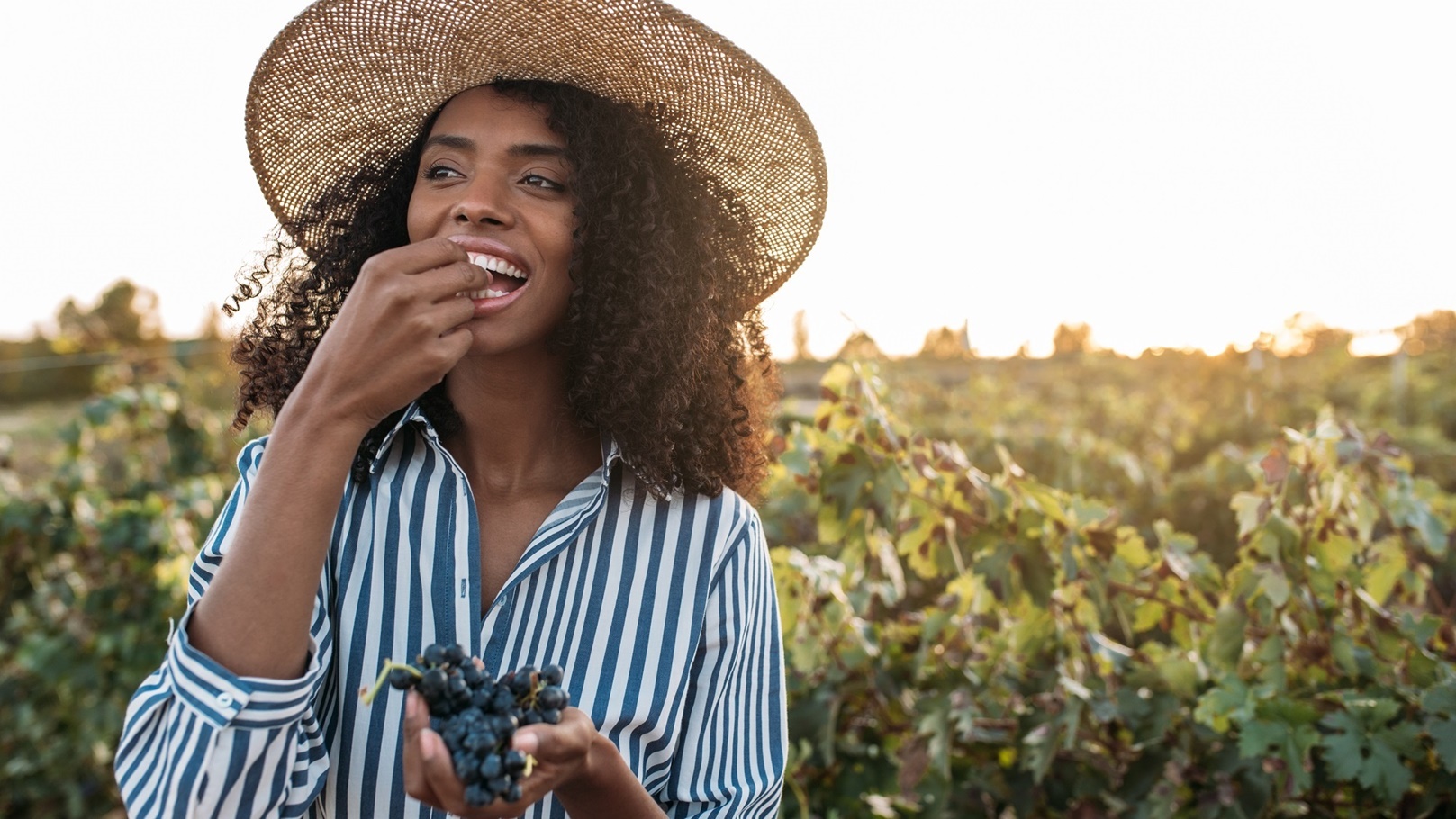 happy-young-woman-in-a-straw-hat-eating-grapes-in-2021-08-26-20-17-10-utc
