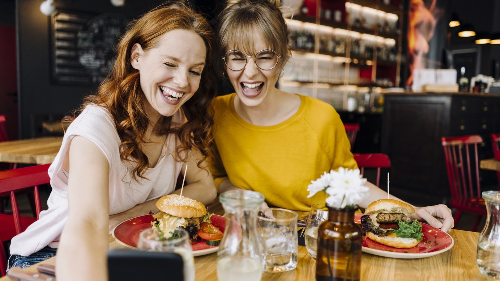two-happy-female-friends-having-burger-and-taking-2022-03-08-01-25-05-utc