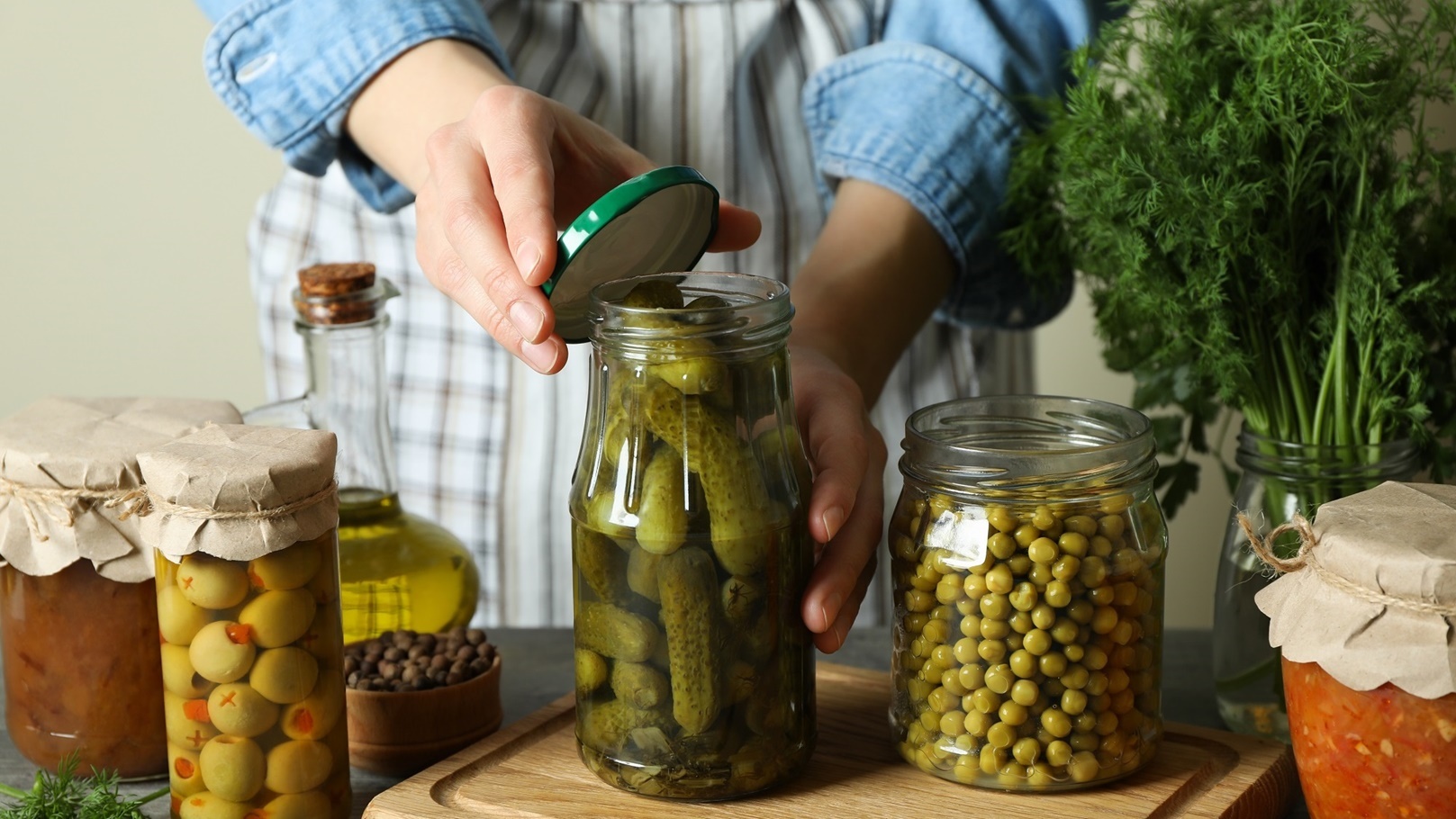 woman-closes-a-jar-of-pickled-cucumbers-on-wooden-2021-08-31-23-38-33-utc